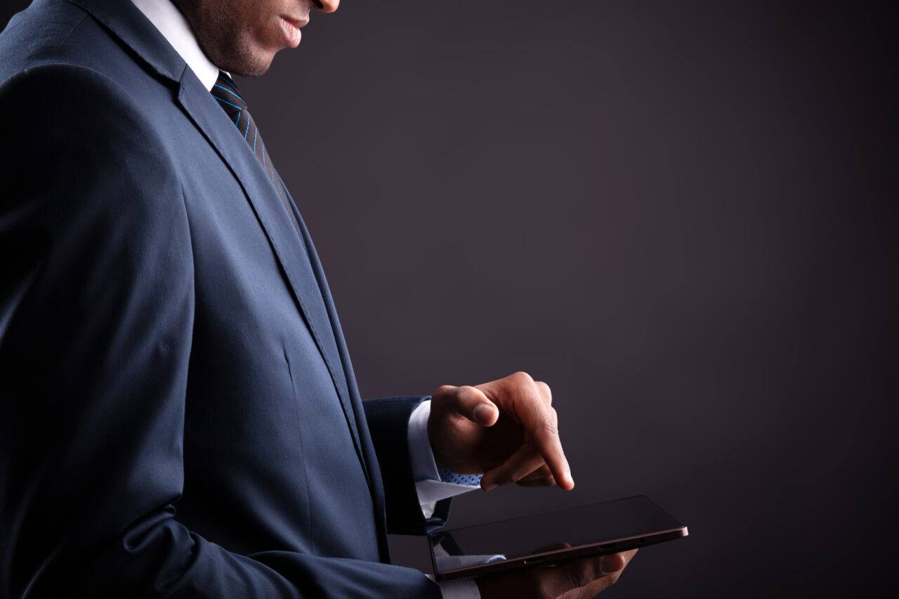 Businessman holding digital tablet on black background
